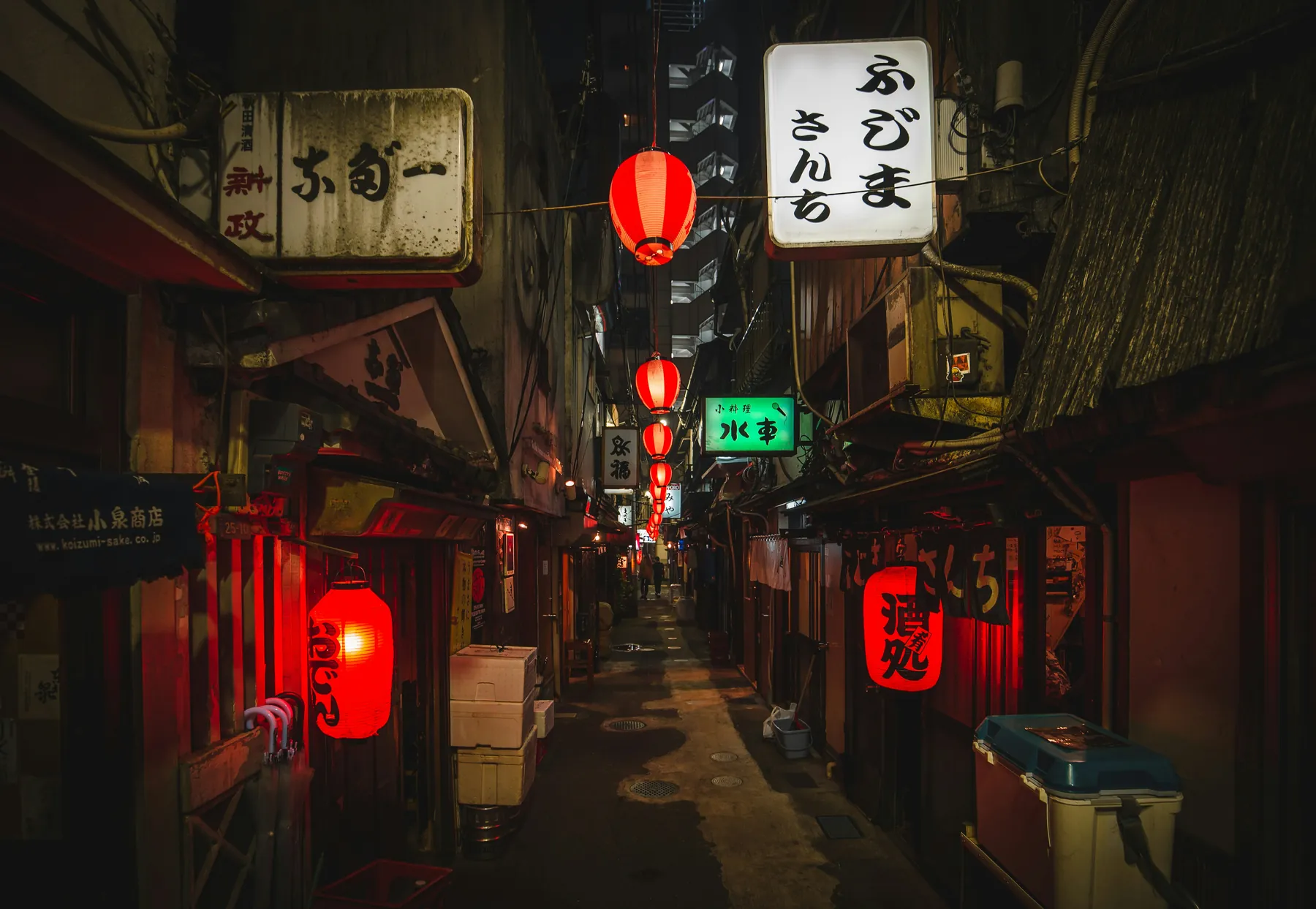 En smal Tokyo-gyde om natten kantet med glødende røde lanterner og oplyste skilte