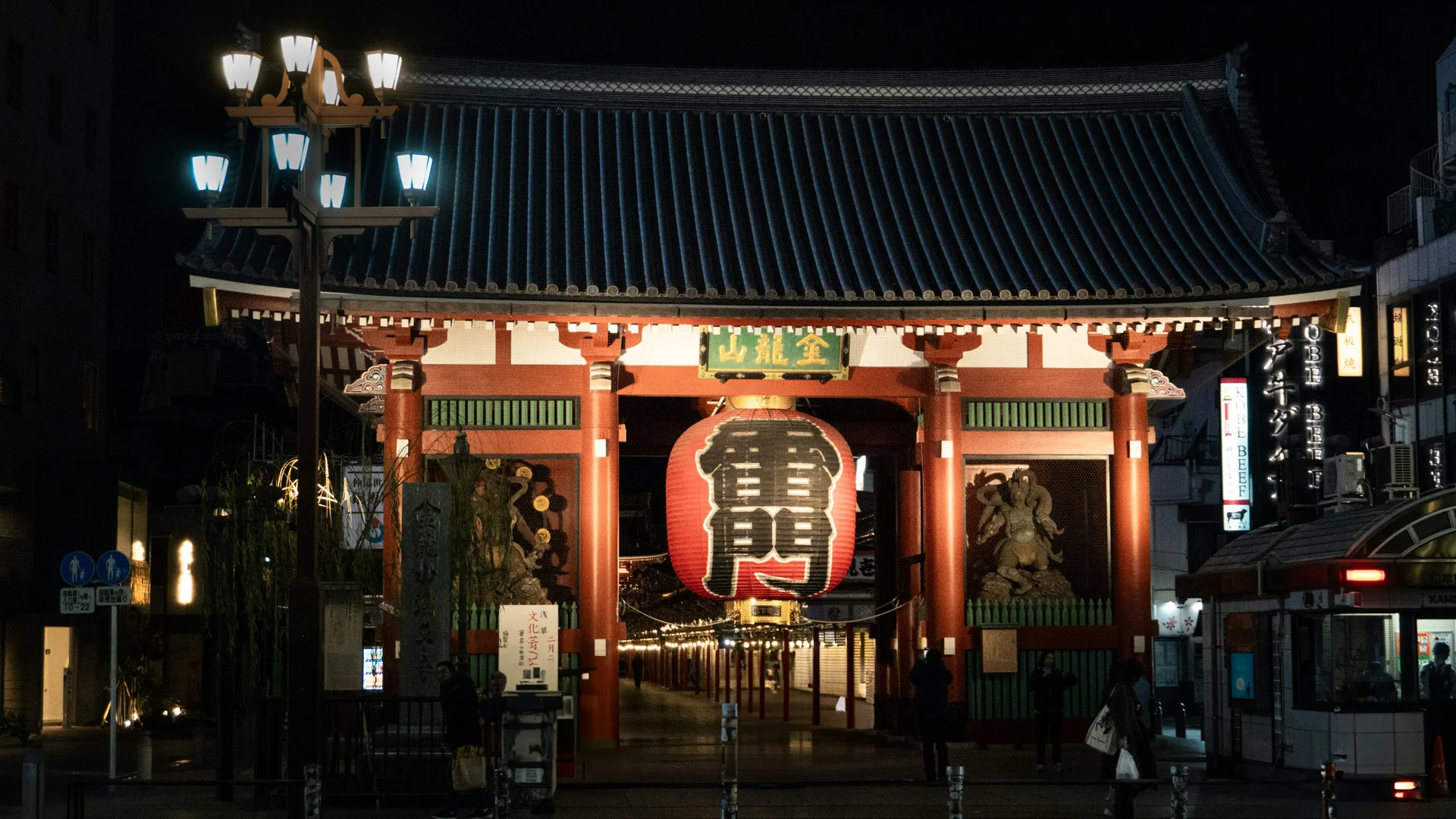 Kaminarimon-porten i Asakusa om natten, hvor den gigantiske røde lanterne lyser mellem to statuer under et mørkt tegltag